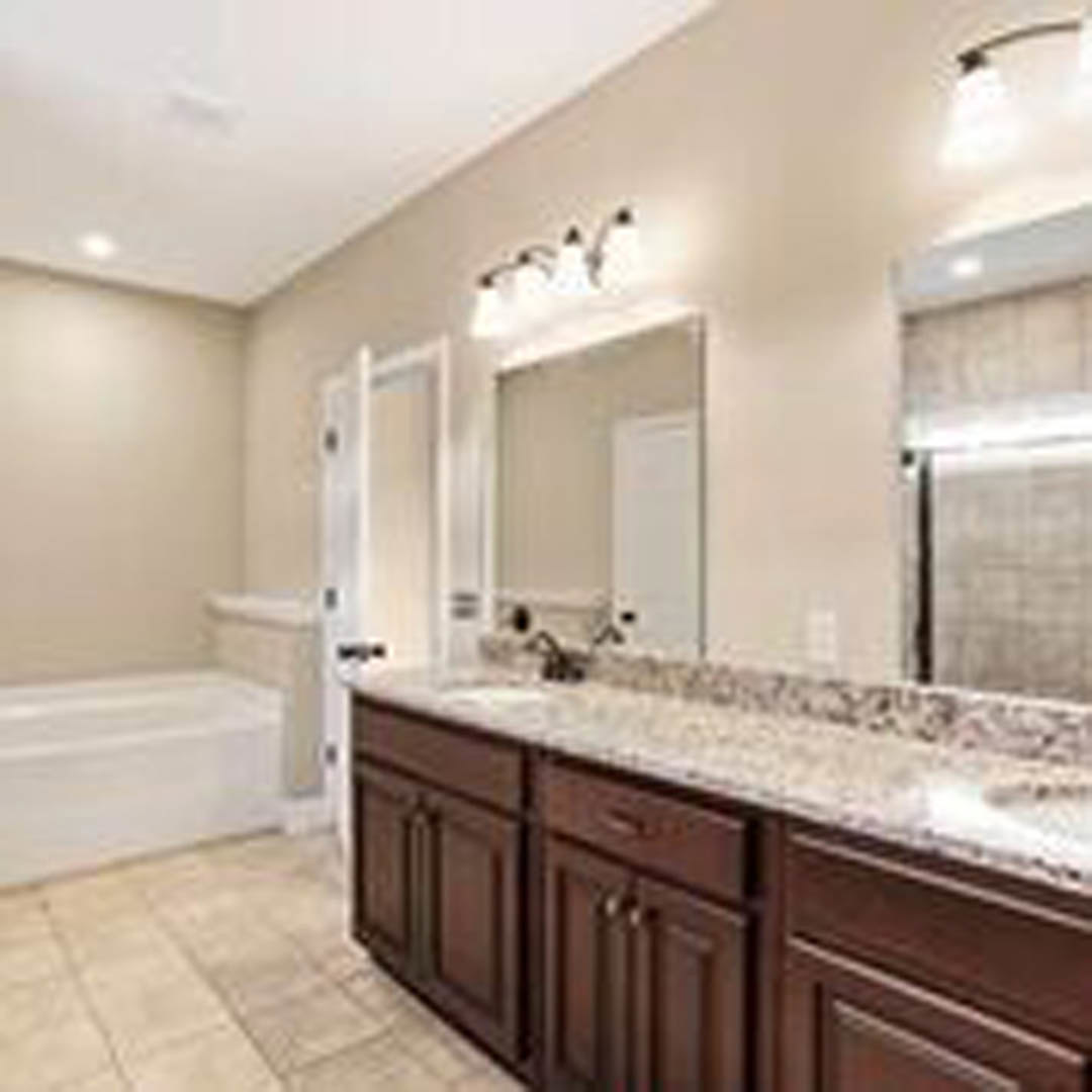 Bathroom featuring a marble countertop with undermount sink, freestanding bathtub, tile flooring, and white cabinetry
