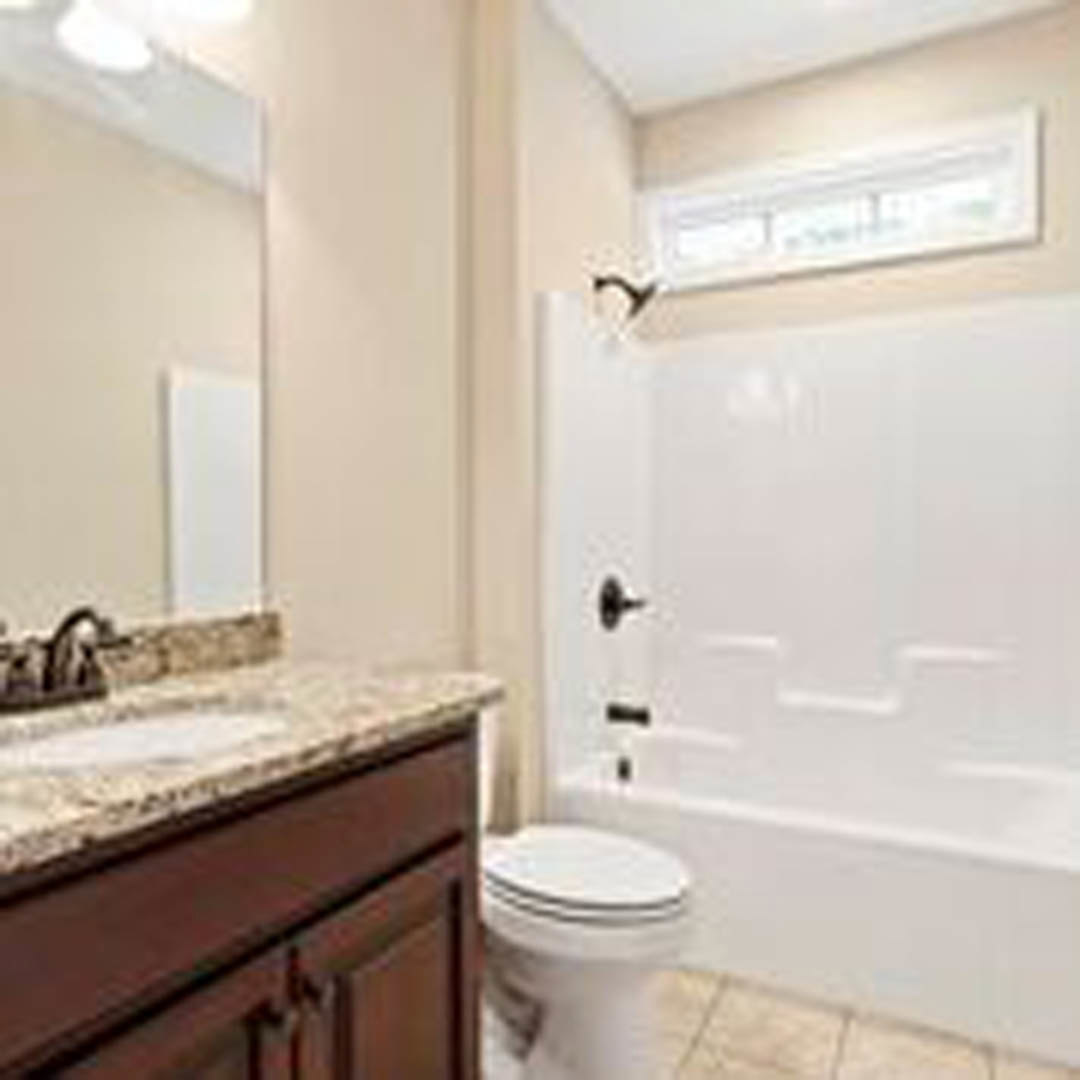 Modern bathroom featuring a white bathtub, toilet, wall-mounted sink, light gray tile flooring, and chrome fixtures