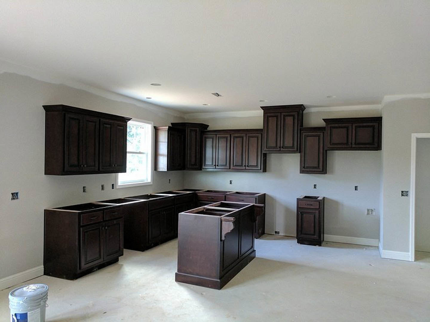 Kitchen featuring dark wood cabinets, white framed window, stainless steel appliances, light countertops, and neutral flooring