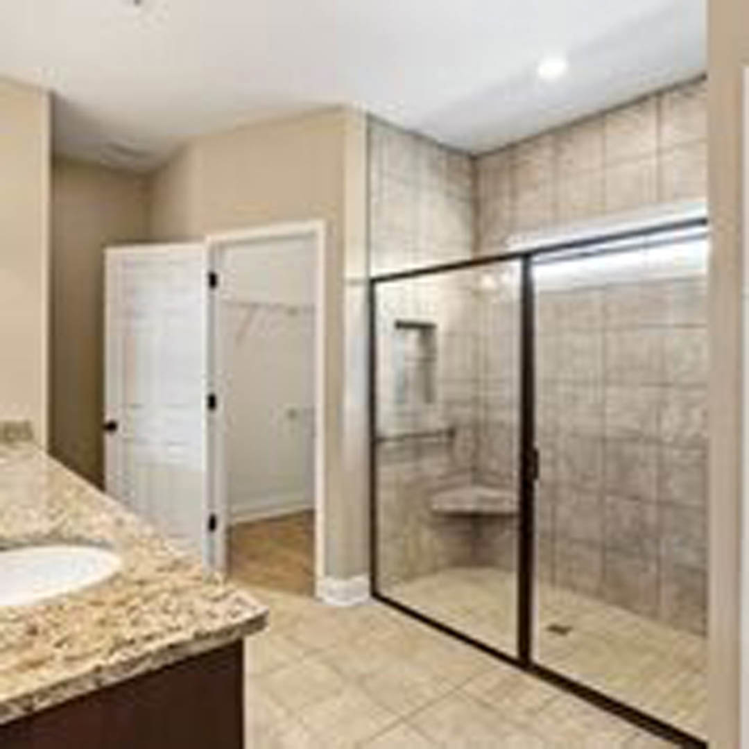 Modern bathroom featuring a glass-enclosed shower with white tile walls, a floating vanity with vessel sink, chrome faucet, and light wood cabinetry.
