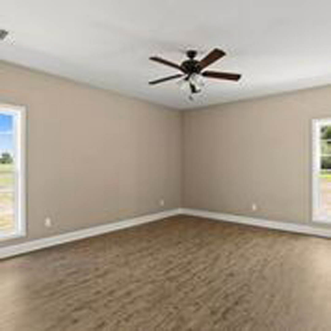 Neutral-toned room with brown carpet, white walls, ceiling fan with light fixture, and multiple windows letting in natural light