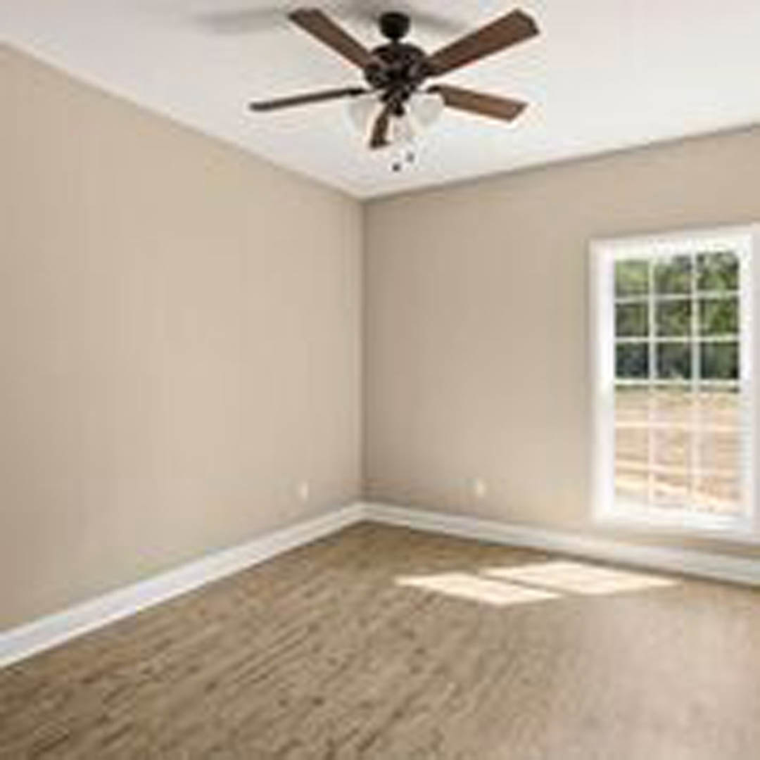 Ceiling fan with light fixture mounted above wood flooring and white baseboards, single window with white trim on neutral painted wall