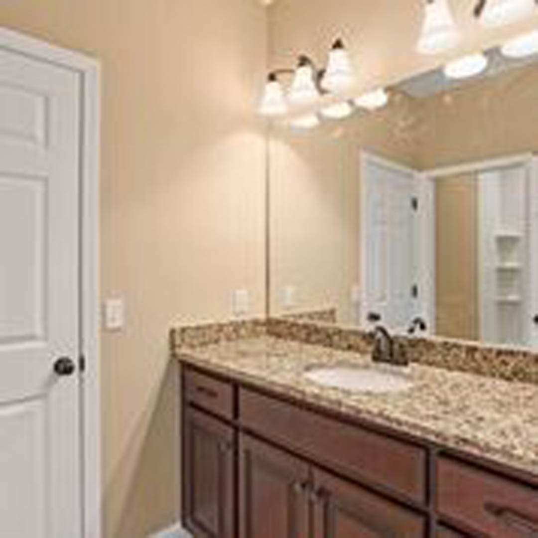 Marble countertop with undermount sink, chrome faucet, white cabinetry, and tiled backsplash in a modern bathroom.