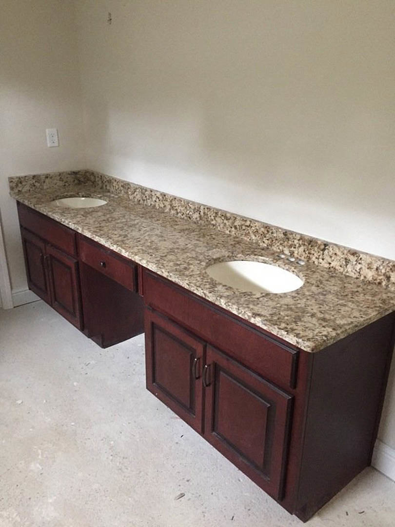 Bathroom with double sinks set in a marble countertop, white cabinetry below, chrome faucets, light tile flooring, and neutral wall finishes.