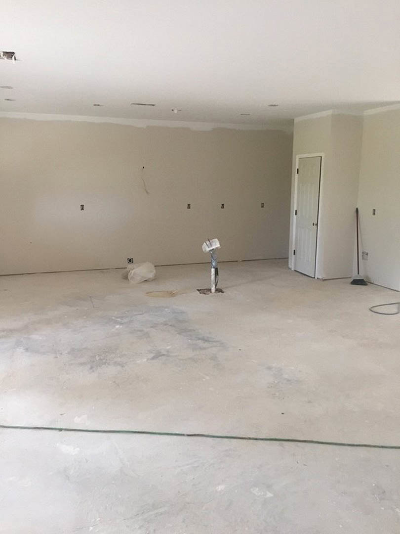 White-painted room with smooth plaster walls, white door featuring black handles, white concrete floor with a small hole, exposed electrical wires on wall, white plastic bag
