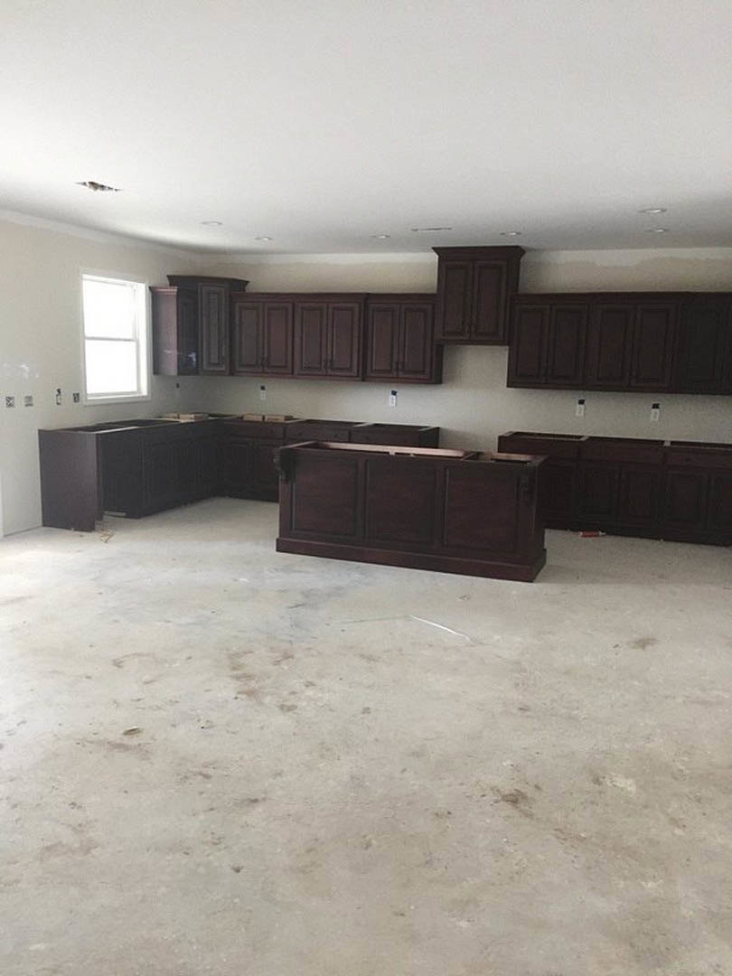 Kitchen featuring dark wood cabinetry, white walls, sunlit window, white ceiling, black door, and light-colored flooring.