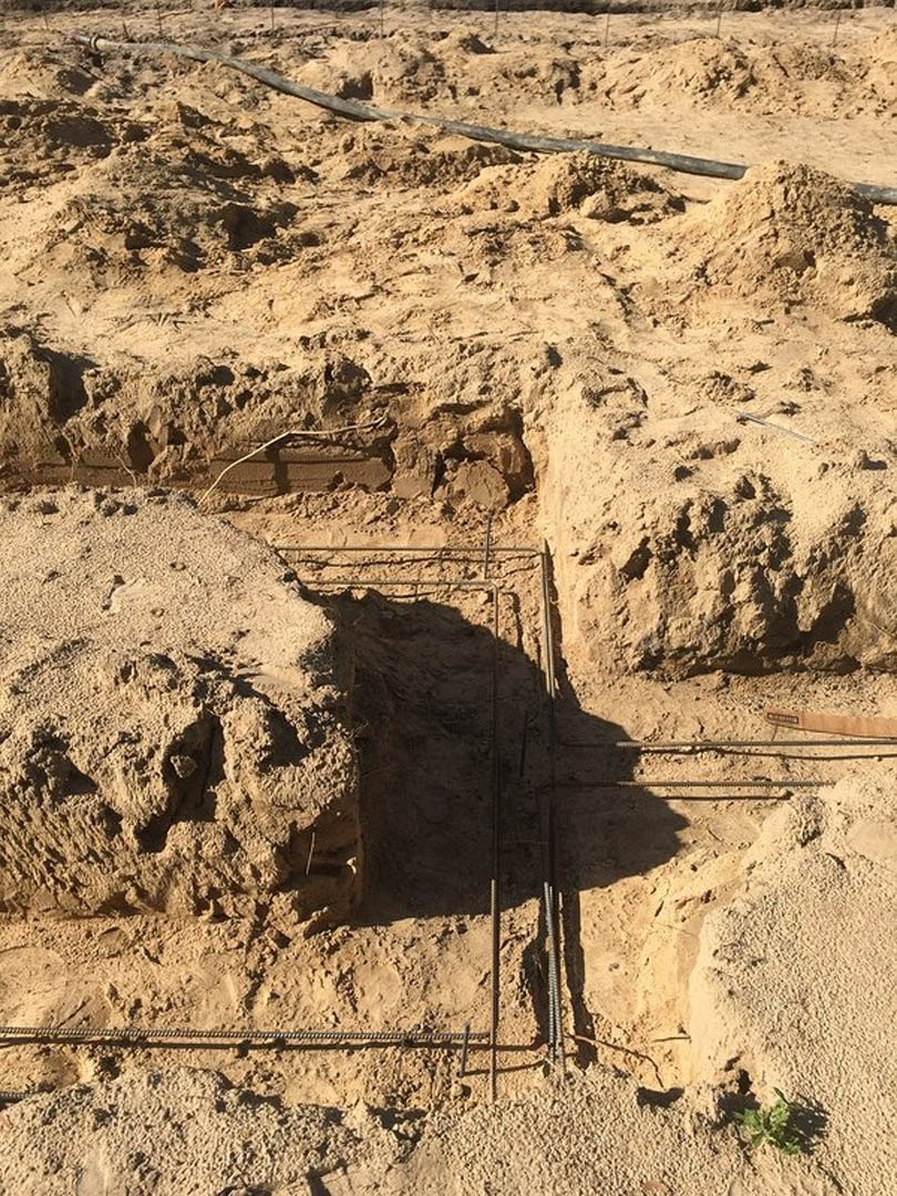 Dirt construction site with exposed metal rods protruding from soil