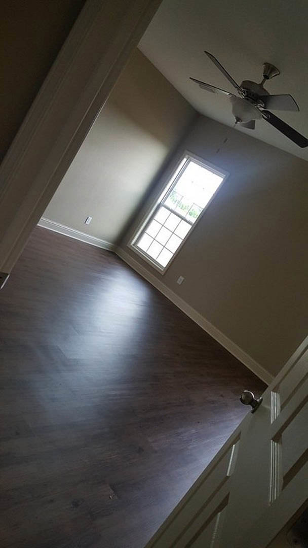 Wood floor room with white-framed window, plaster walls, and ceiling fan with light fixture