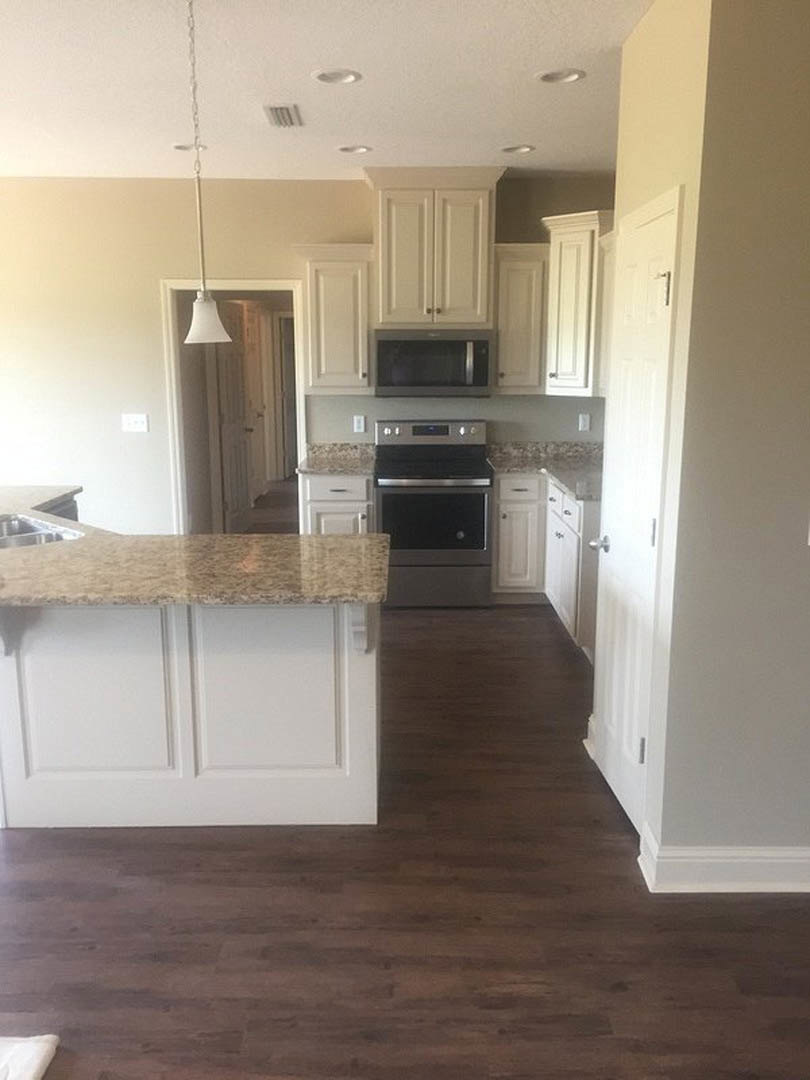 Kitchen with granite countertops, stainless steel microwave, white cabinetry, kitchen island, window, white ceiling fan, and tiled floor