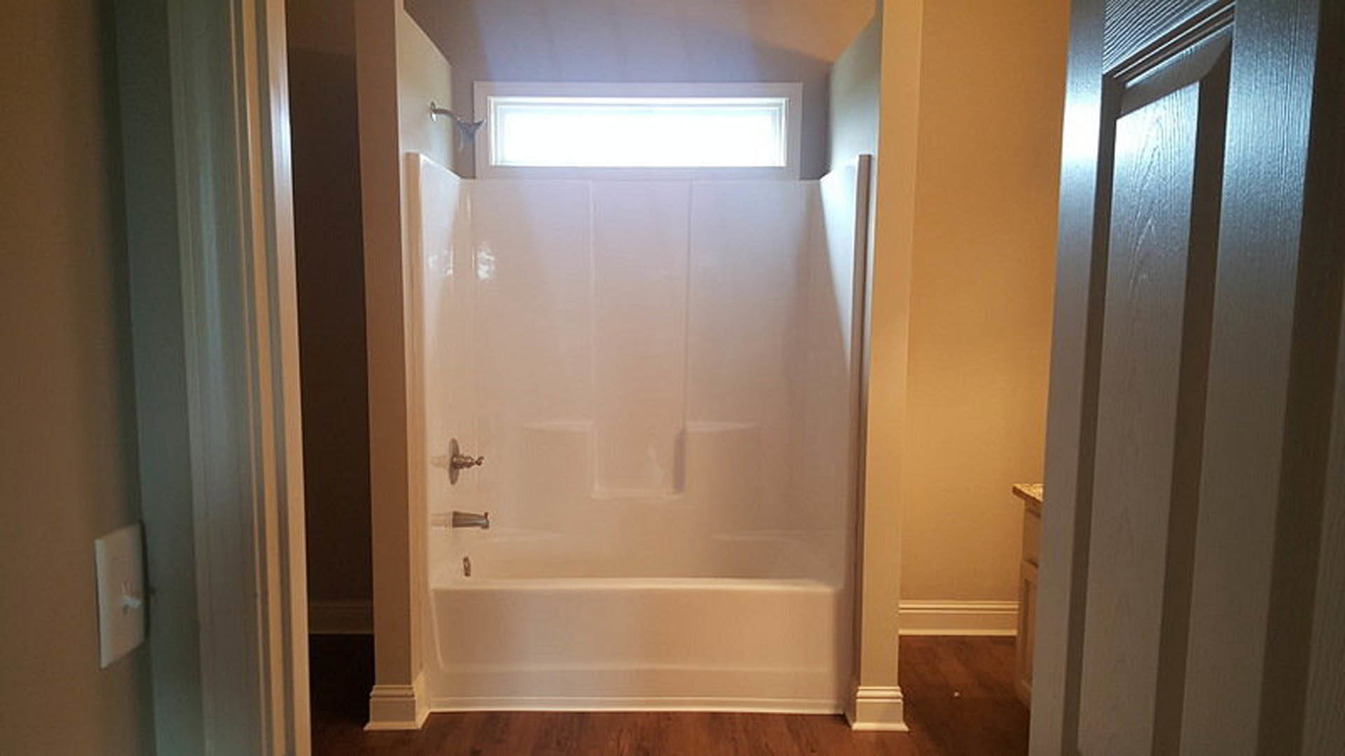 White tile shower with glass door, chrome fixtures, and built-in niche in modern bathroom.
