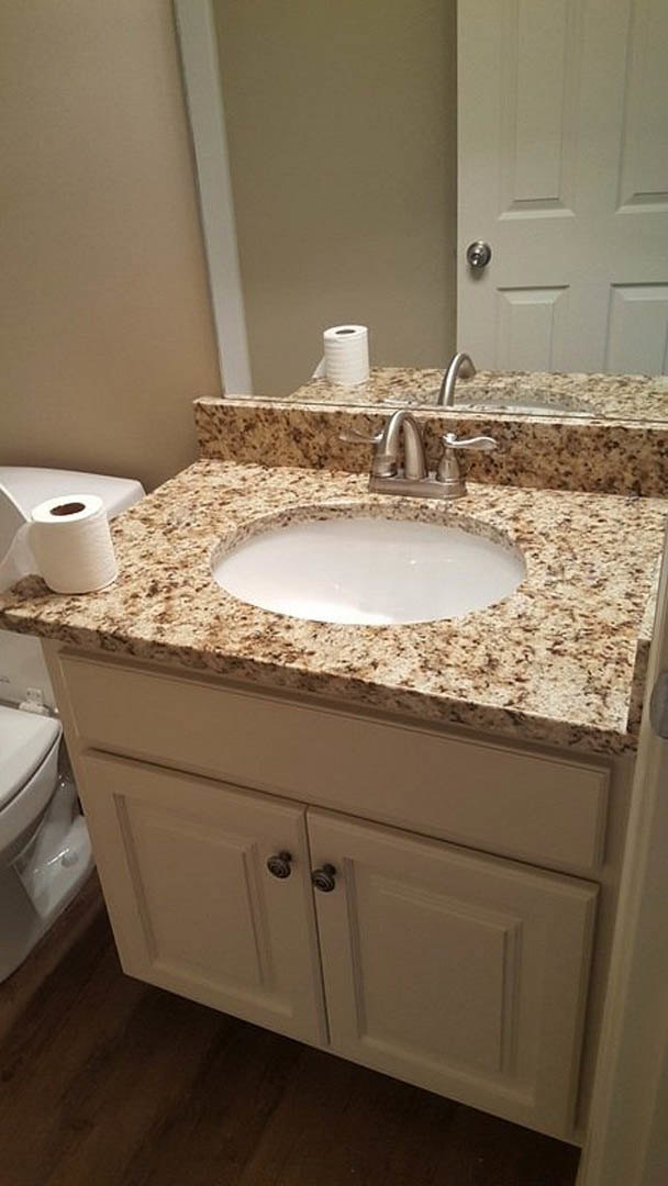 Modern bathroom with white ceramic sink, chrome faucet, white toilet, brown wood vanity, and toilet paper roll on tiled floor