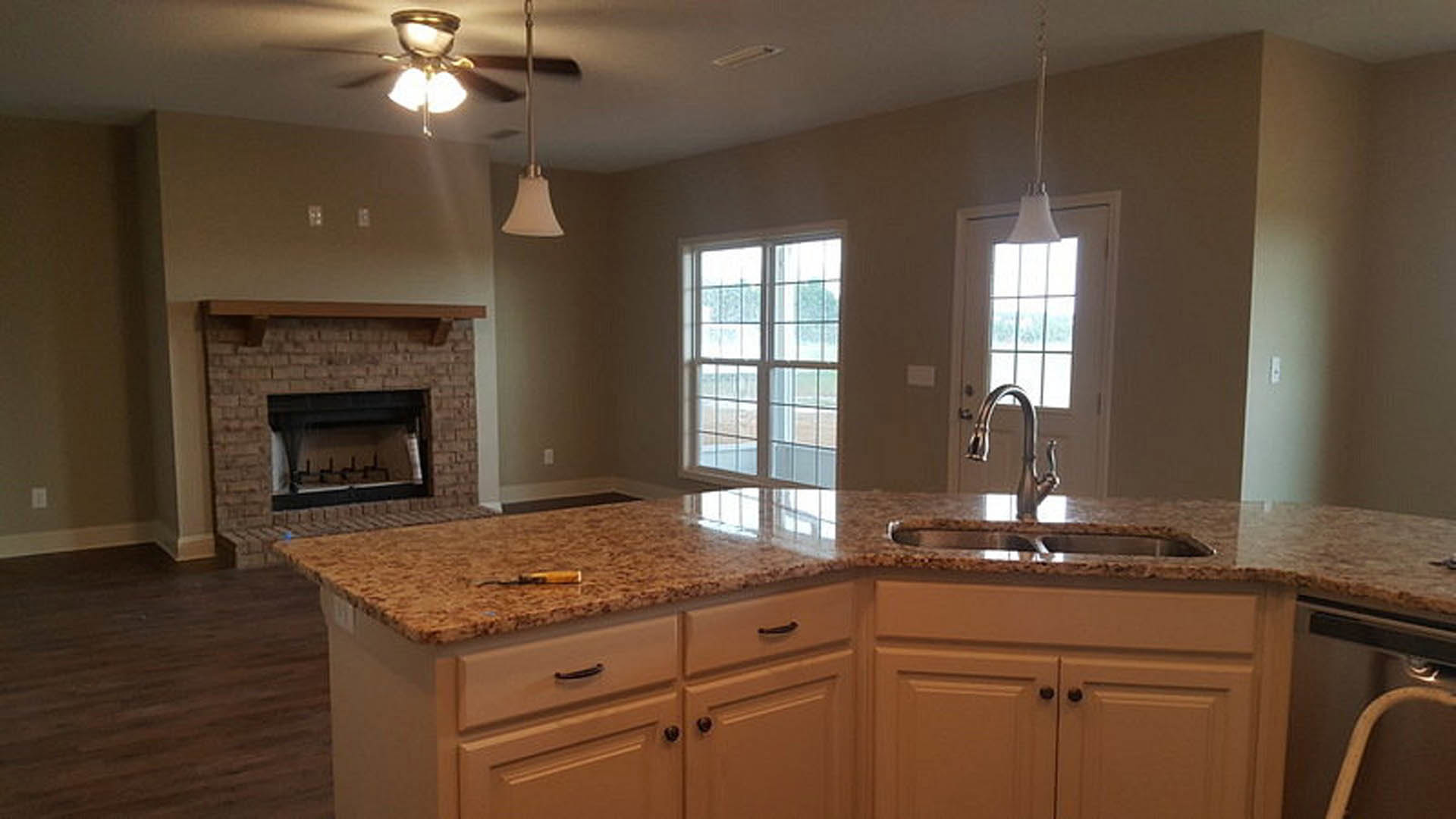 Modern kitchen featuring white cabinetry, stone countertop with stainless steel sink and faucet, built-in fireplace on adjacent wall, large window providing outdoor view, and sleek
