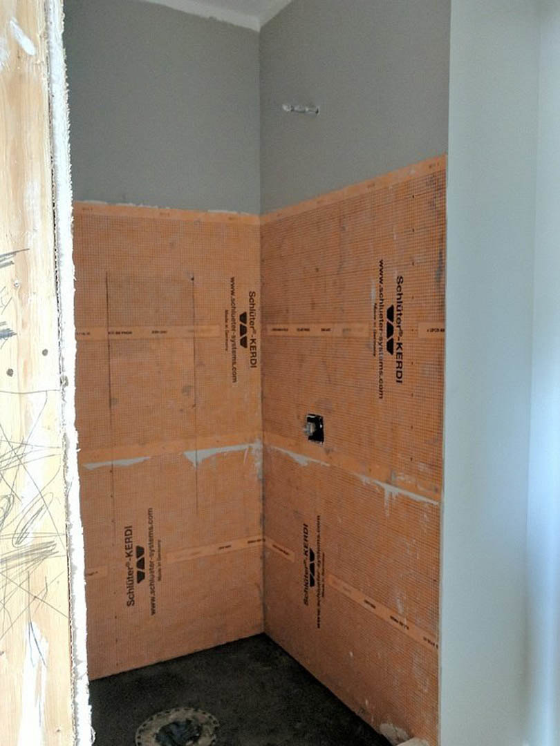 White-painted walls and door, light wood flooring, black carpet in corner, close-up of wood trim