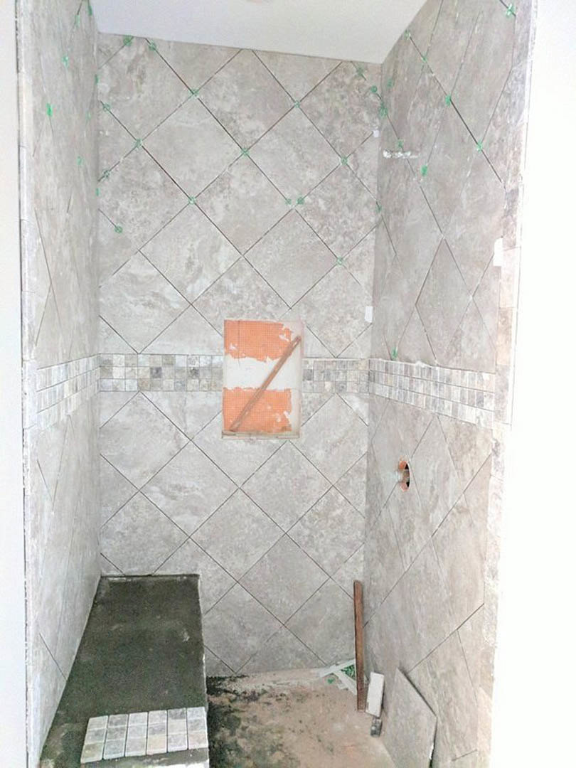 Modern bathroom featuring marble tile walls, glass shower enclosure, and white plaster finishes.