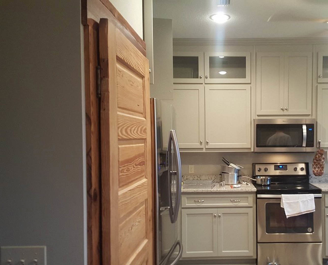 White kitchen with shaker cabinets, stainless appliances, white towel draped over oven handle, light countertops, and tile backsplash.