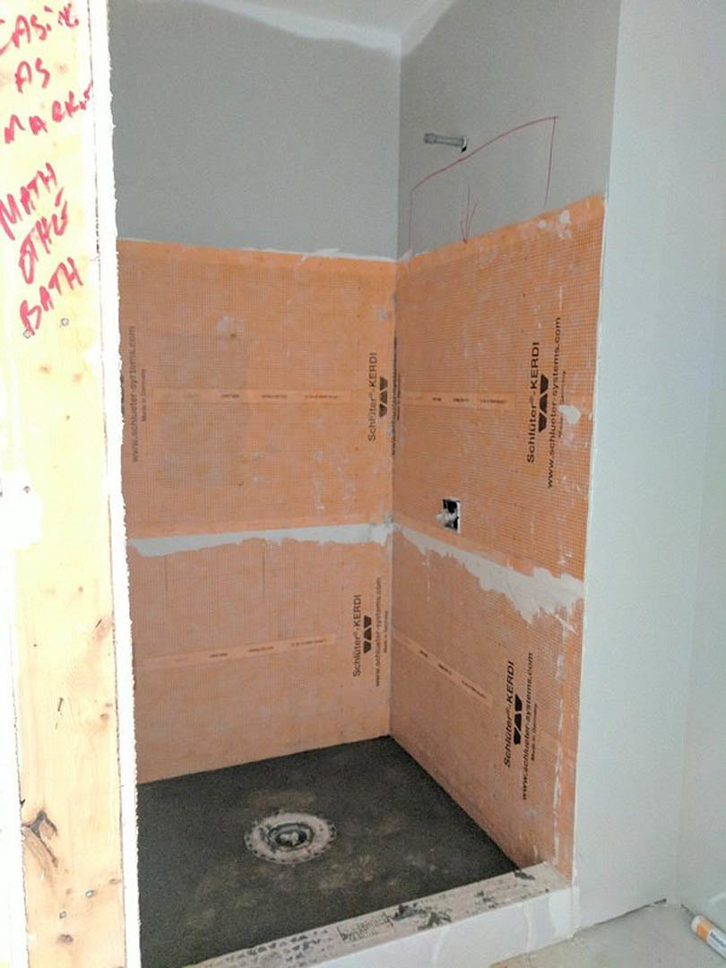 Shower room with yellow walls, circular hole cut into wall, tiled floor, and visible shower drain