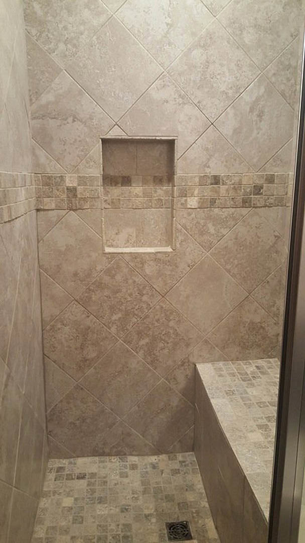 Walk-in shower featuring marble tile walls, built-in shelf niche, and tiled floor with linear drain