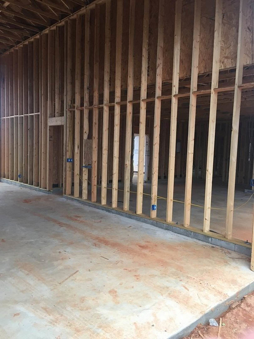 Wood framing structure with exposed beams and concrete floor inside a residential home under construction