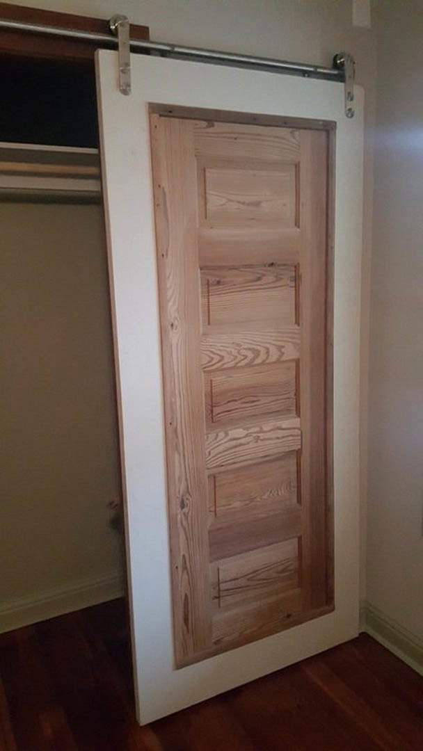 Close-up of a wooden door with visible grain, silver door handle, and hardwood flooring adjacent to white plaster walls
