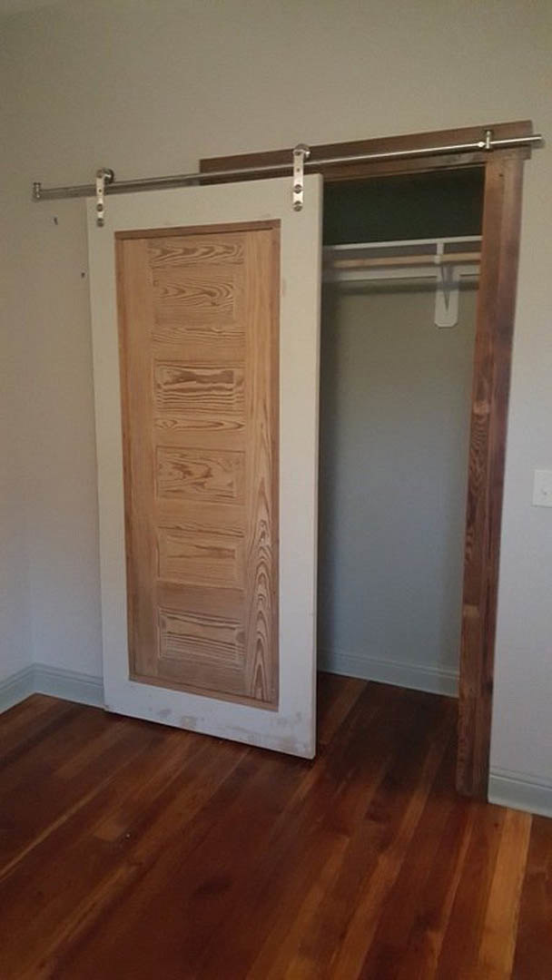 White closet door partially open over light hardwood plank flooring, adjacent to smooth white plaster wall