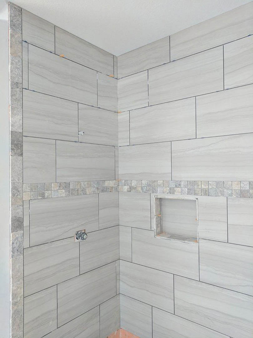 Bathroom with white tile walls, built-in shelf, and smooth tile surfaces