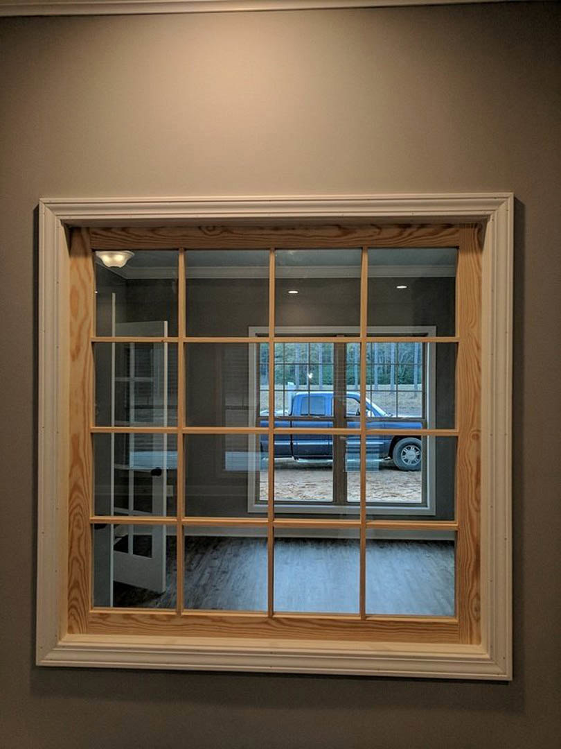 Wood-framed window with white blinds, adjacent door, blue truck parked outside on driveway