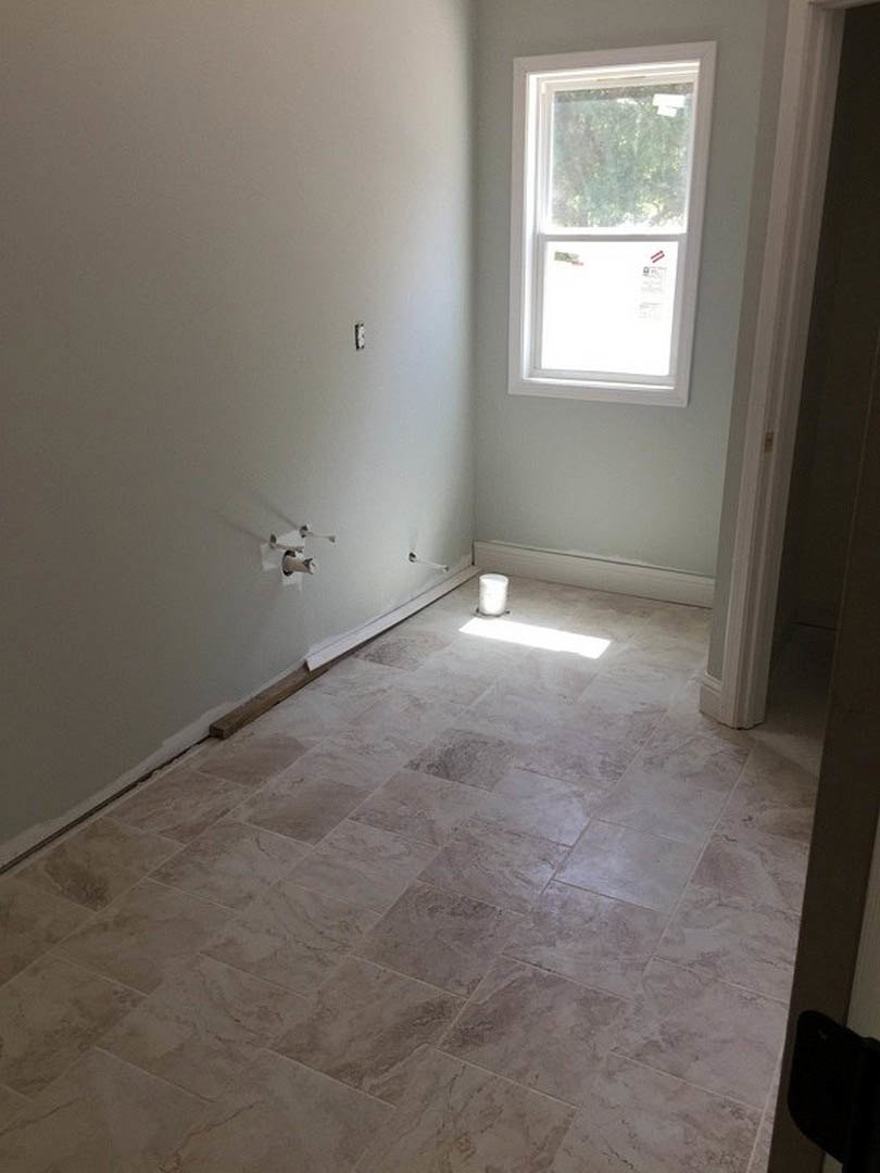 Sunlit room with white tile flooring, white-framed window, plaster walls, and smooth white ceiling