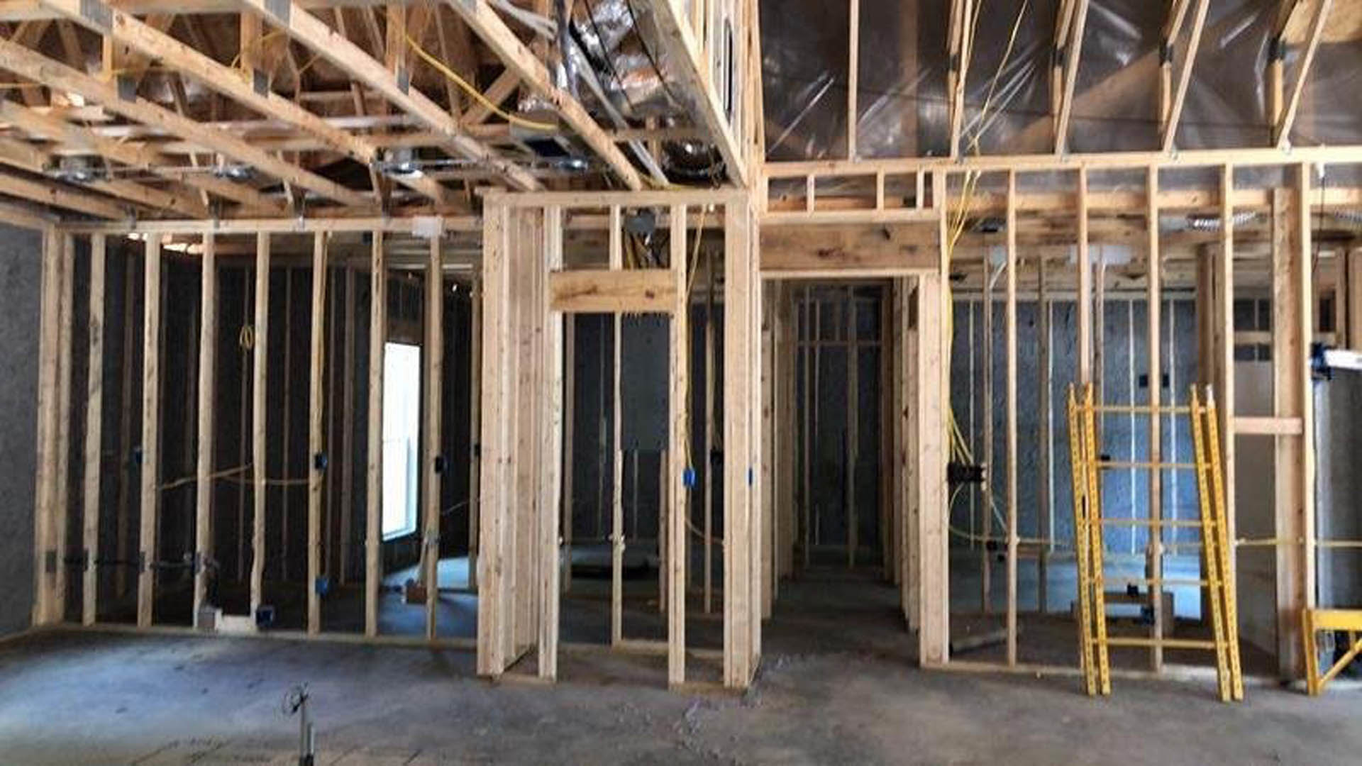 Wood-framed room under construction with exposed beams, unfinished walls, and a window letting in natural light
