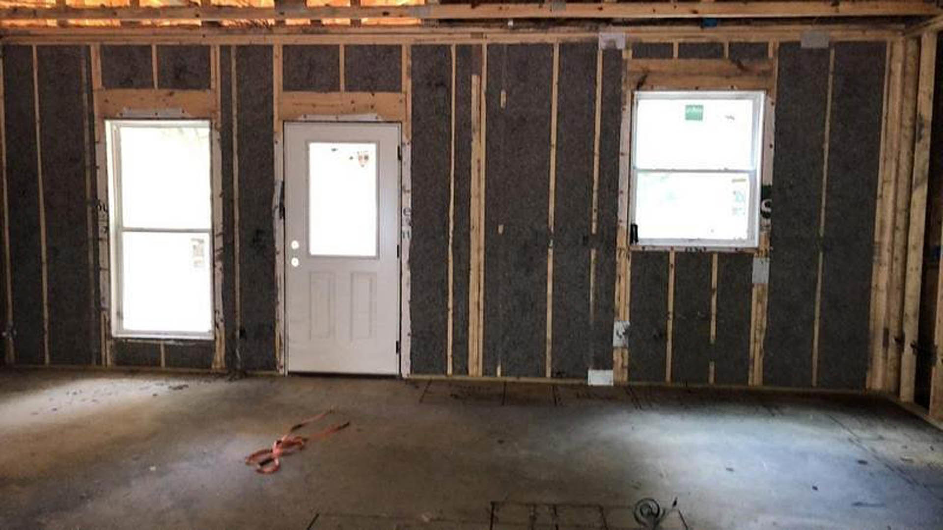 White paneled door and two rectangular windows in a room with light wood trim, painted walls, and visible ceiling beams.