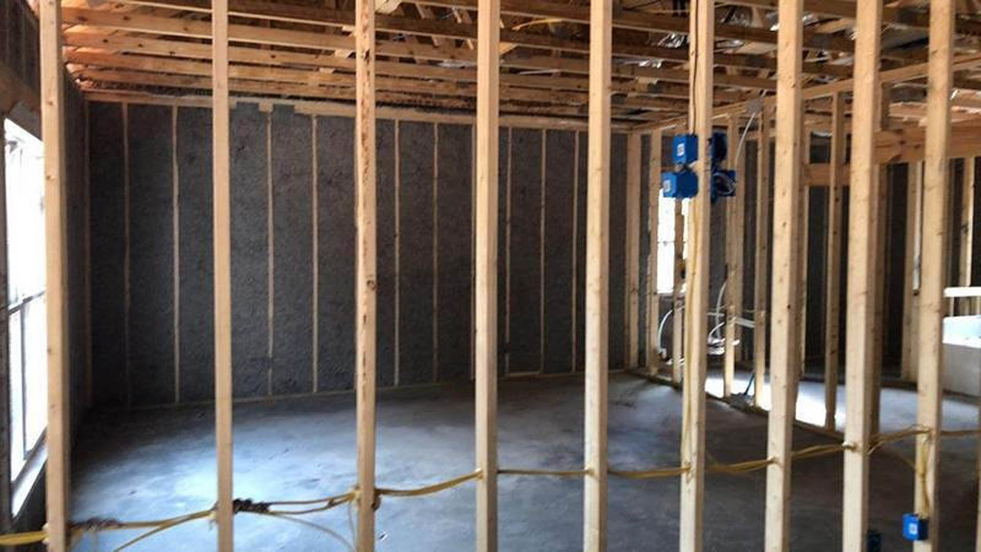Open living space with exposed wood ceiling beams, polished concrete floor, and neutral walls