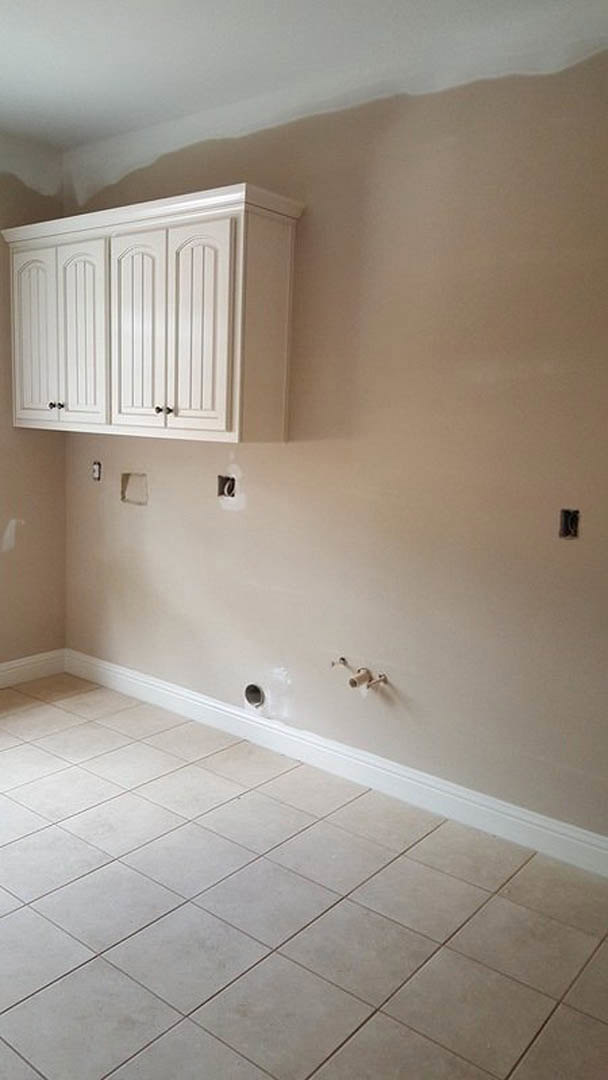 Kitchen with white shaker cabinets, black handles, white tile flooring, light brown accent wall, and plaster ceiling