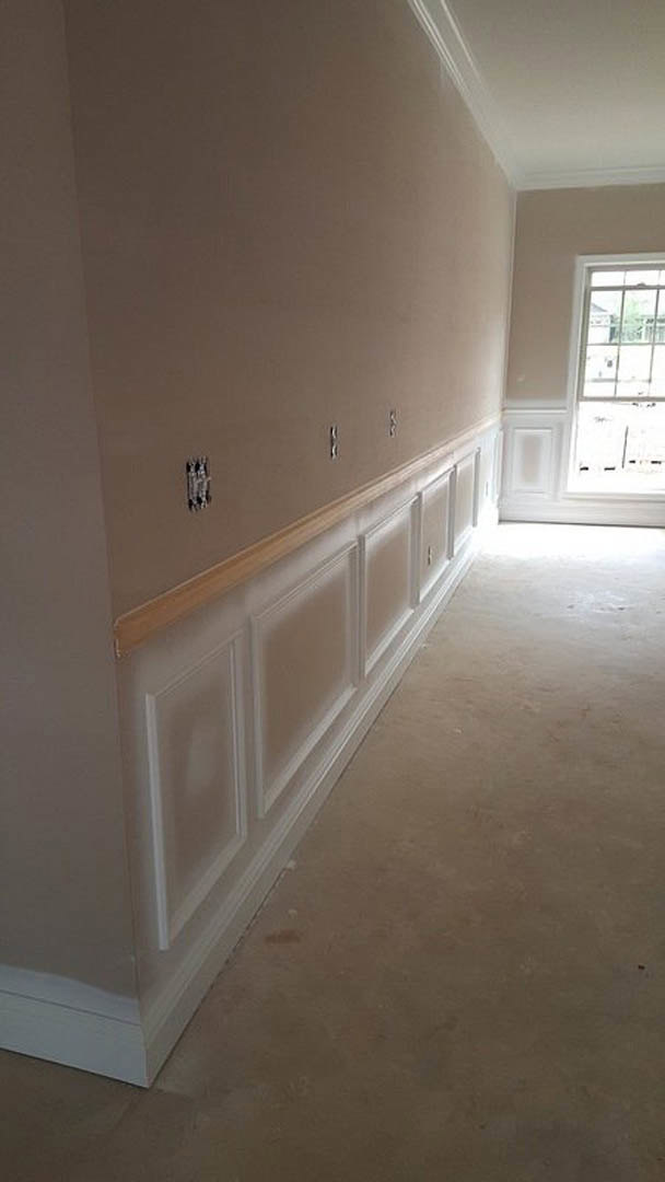 White wall with decorative molding and a multi-pane window letting in natural light