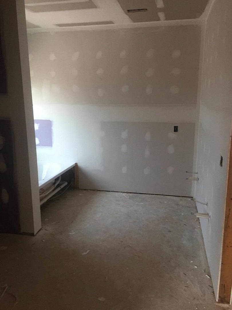 Bedroom with plaster walls, light-colored flooring, simple bed, and white ceiling