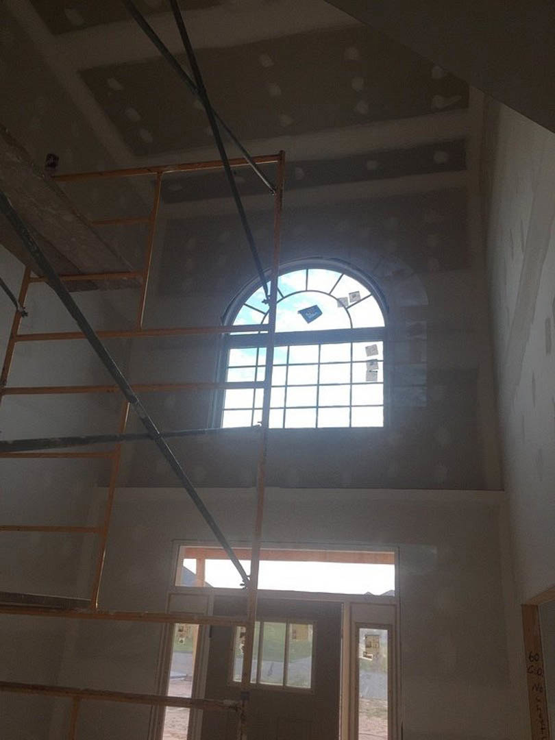 Large window with white trim set in a neutral-toned room, wall-mounted clock nearby, daylight streaming in, partial view of street outside.