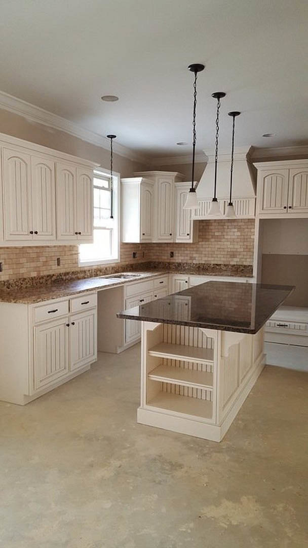 White kitchen cabinets with black handles, marble countertops, central kitchen island with marble surface, brown dining table, white shelving, pendant lights with chain