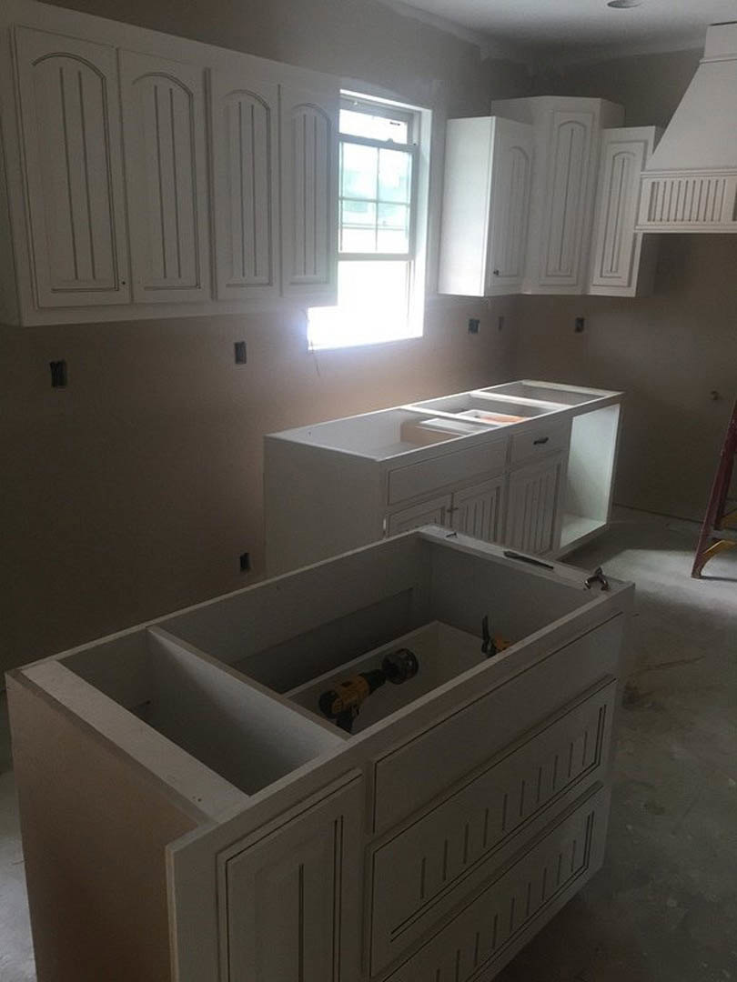 White kitchen cabinets, quartz countertop, window with natural light, drill and red object on open shelf