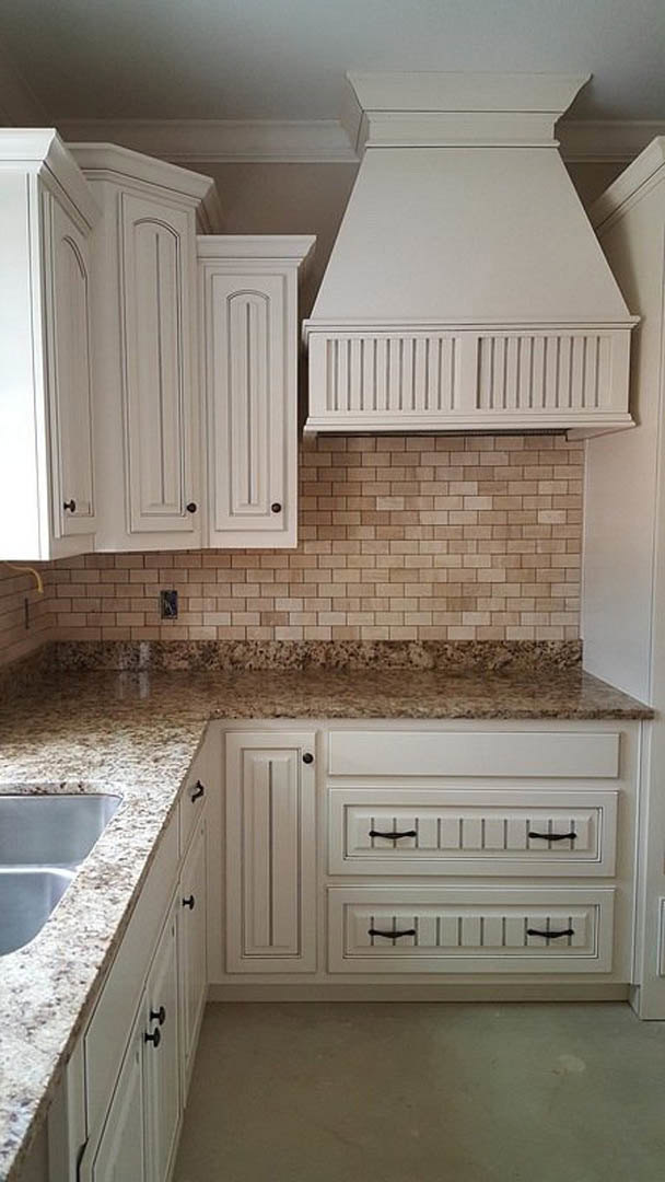 White kitchen cabinets with marble countertops, stainless steel sink, and modern appliances