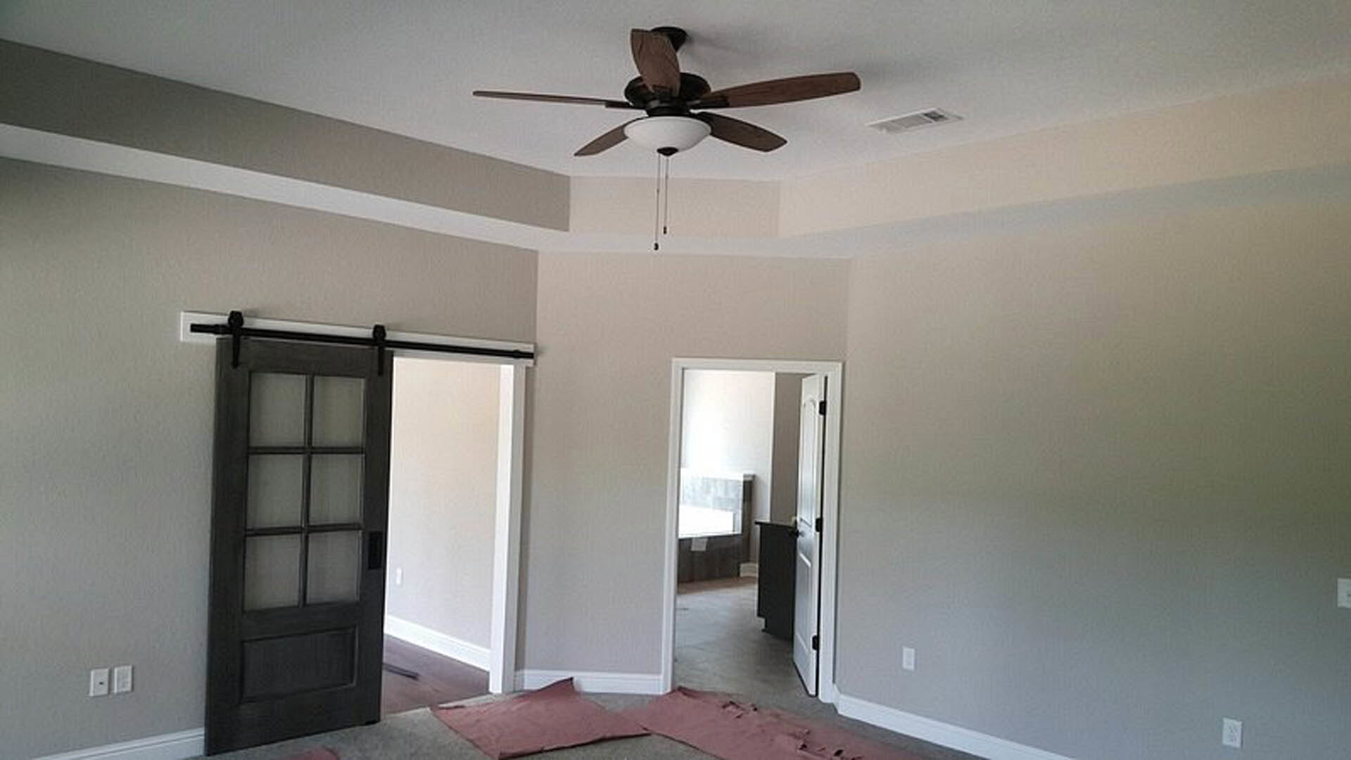 Ceiling fan with integrated light fixture mounted on white plaster ceiling in residential room with neutral walls