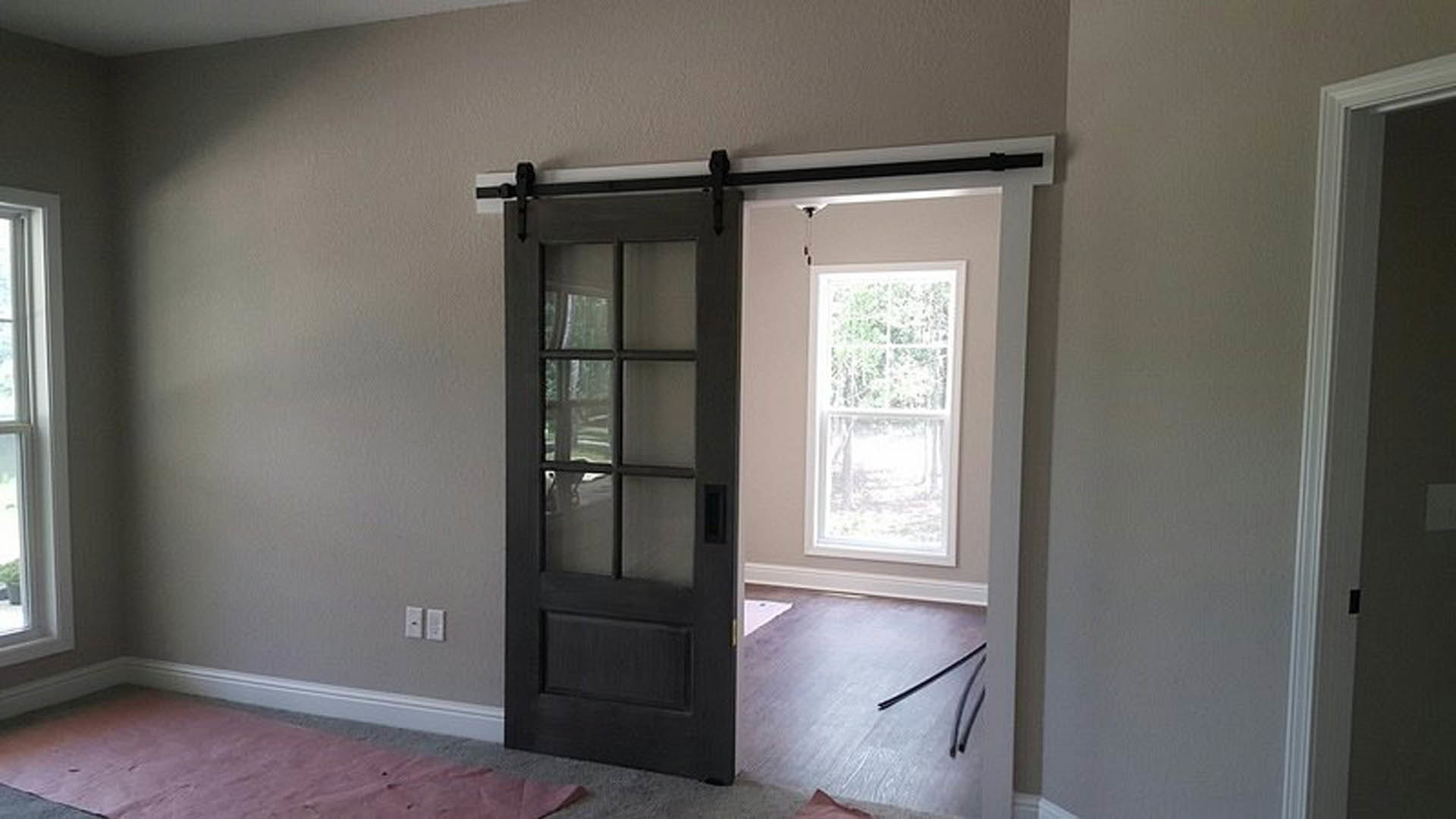 Sliding glass door with black metal handle in a modern room featuring light wood floors and white walls
