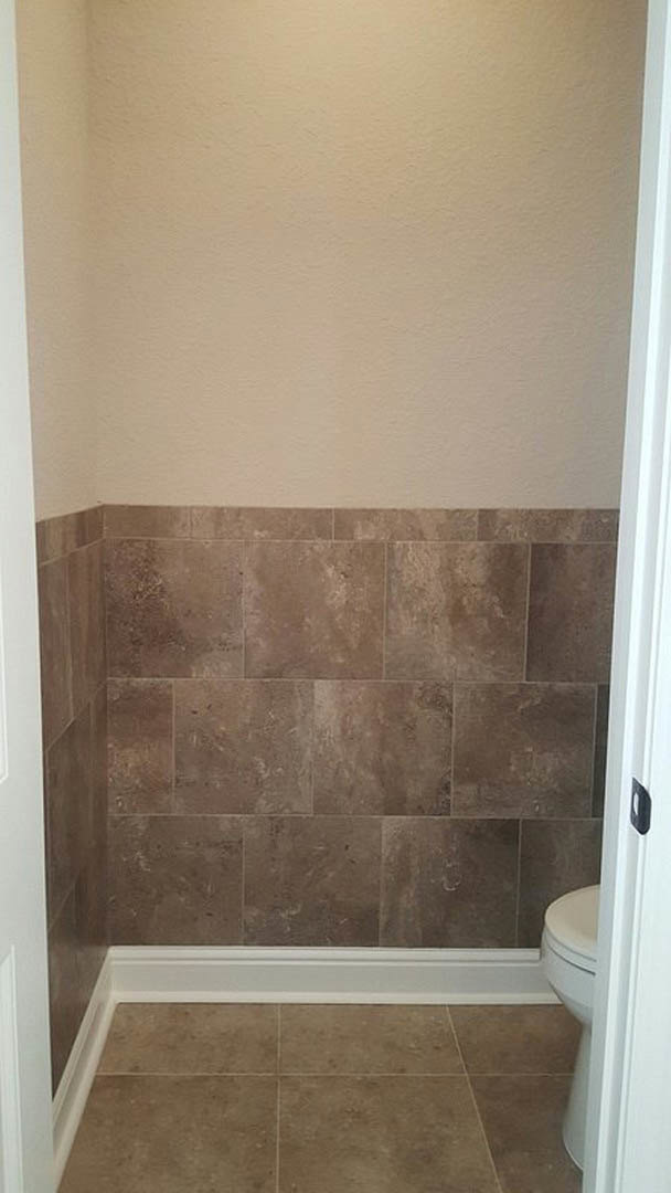 Bathroom with two white toilets, marble tile flooring, plaster walls, and a glass shower enclosure