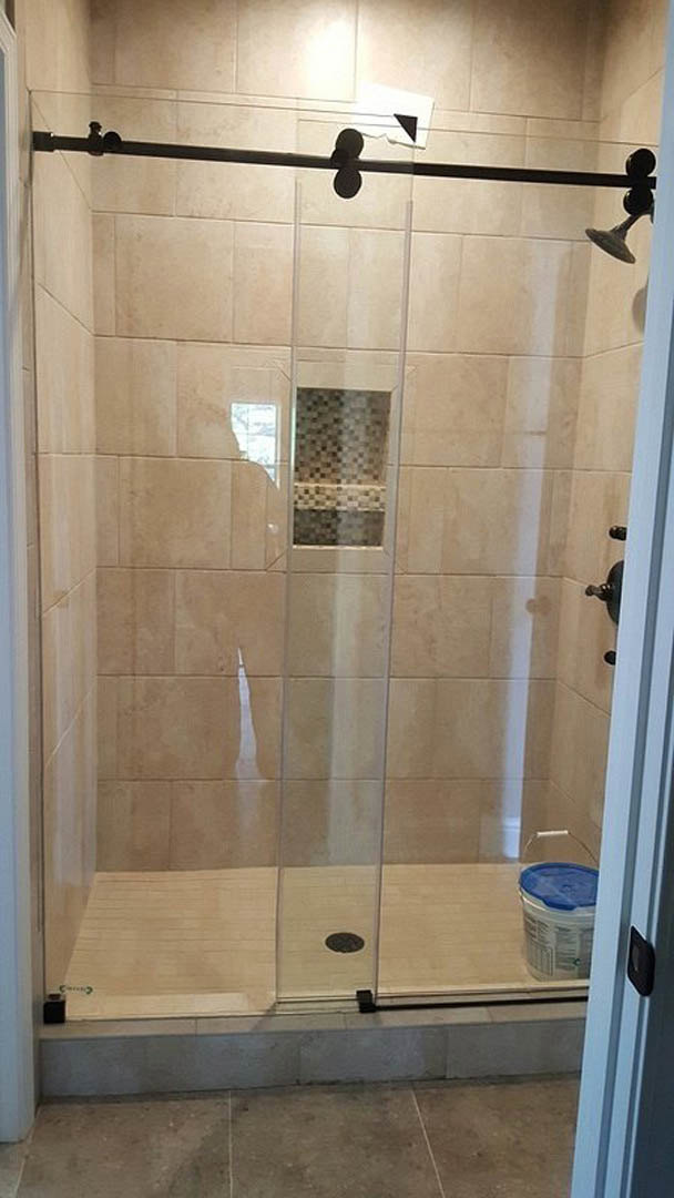 Walk-in shower with clear glass doors, tiled walls, and tile flooring in a modern bathroom