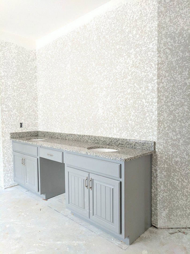 Bathroom with a marble countertop, dual sinks, white cabinetry, and light-colored walls