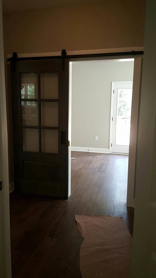 White door with glass panel set in a white plaster wall, brown paper lying on light wood flooring in a modern interior room