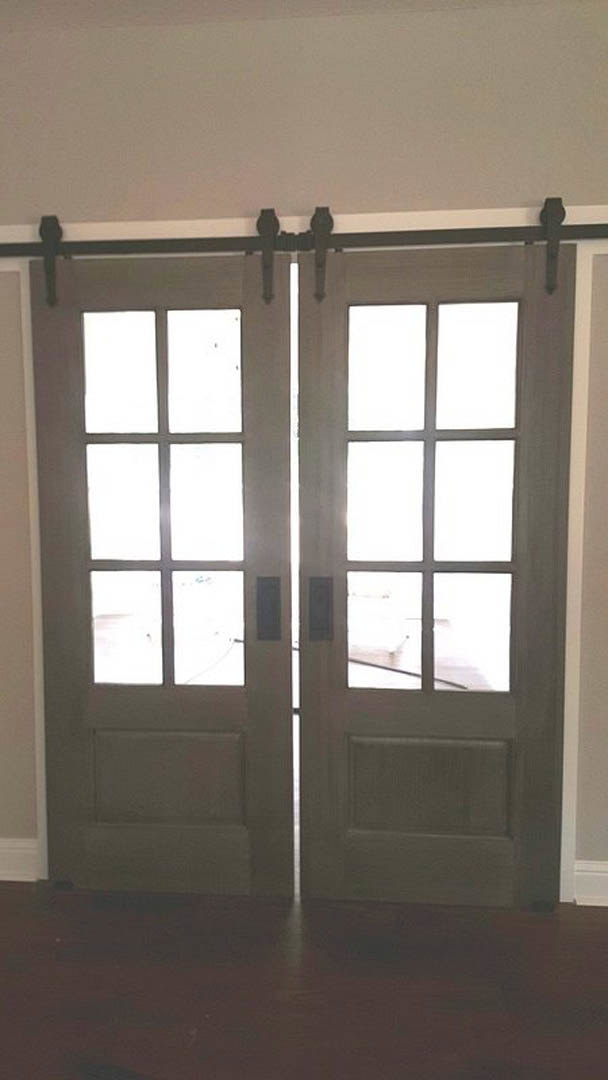 White double doors with glass panes, brushed metal handles, light wood flooring, and neutral walls in a modern interior room