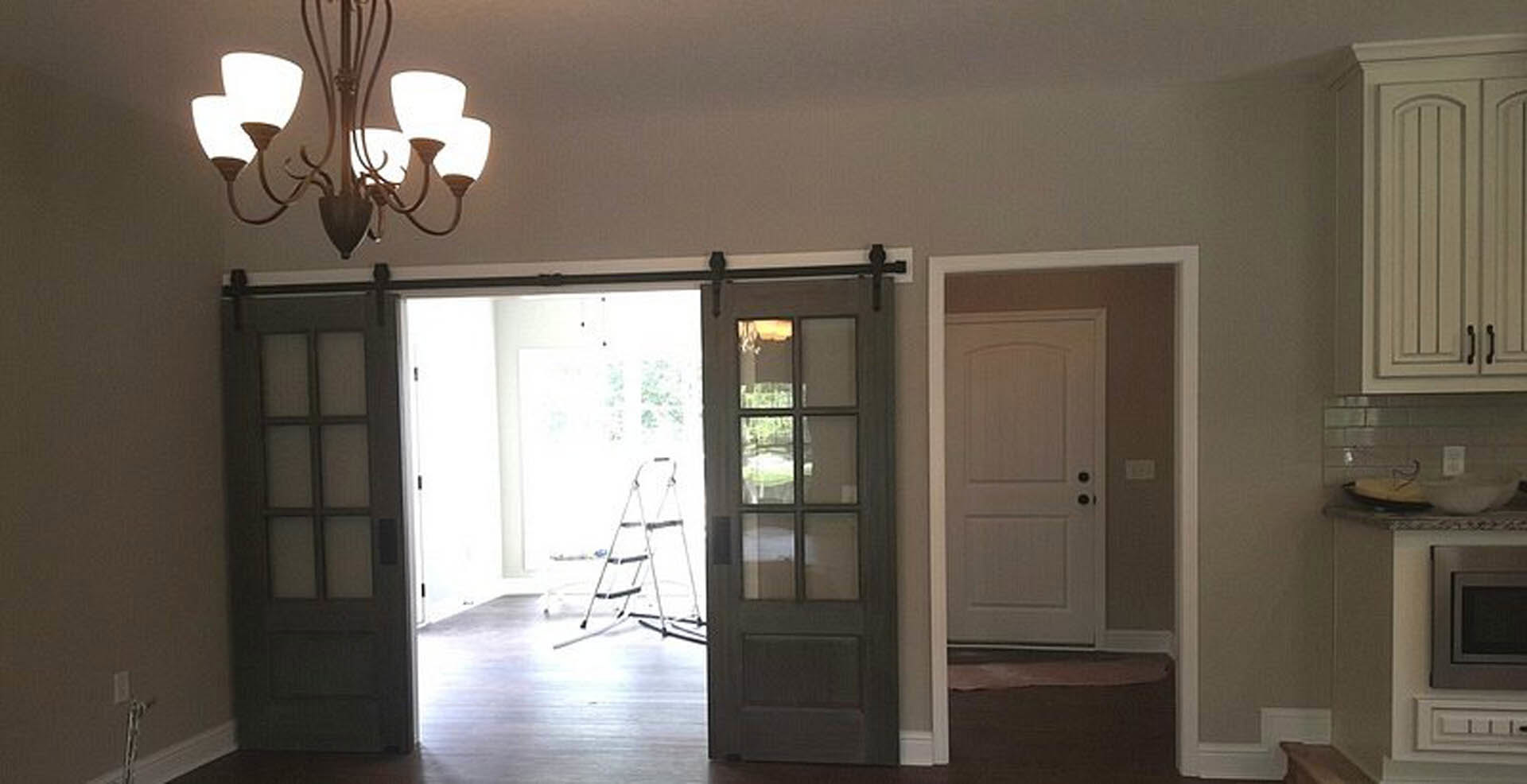 Sliding glass door with white trim in a den, wood flooring, built-in cabinetry, and a television visible on the wall