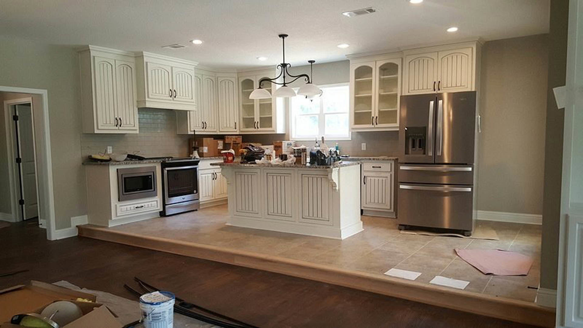 White shaker cabinets, stainless steel refrigerator and oven, built-in microwave, brown hardwood flooring, quartz countertops, undermount sink