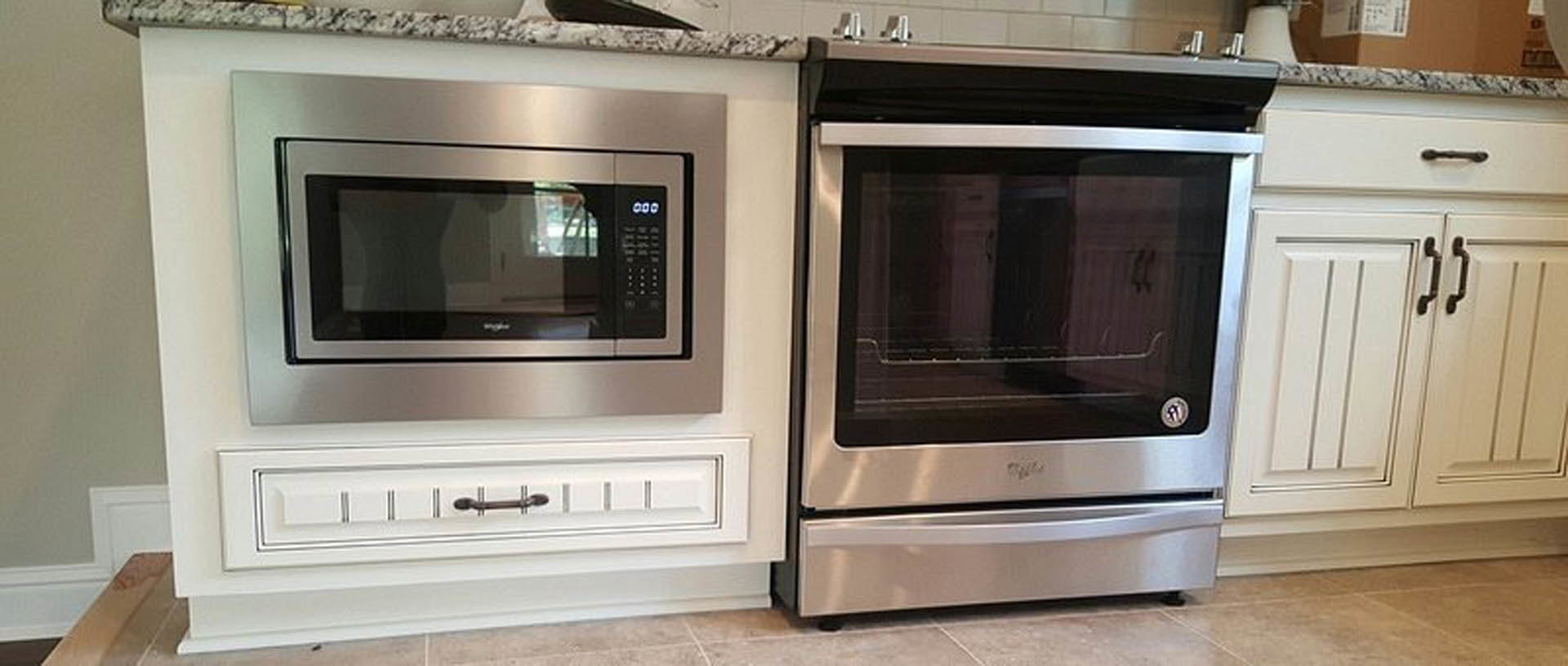Stainless steel microwave and oven built into white cabinetry with quartz countertop
