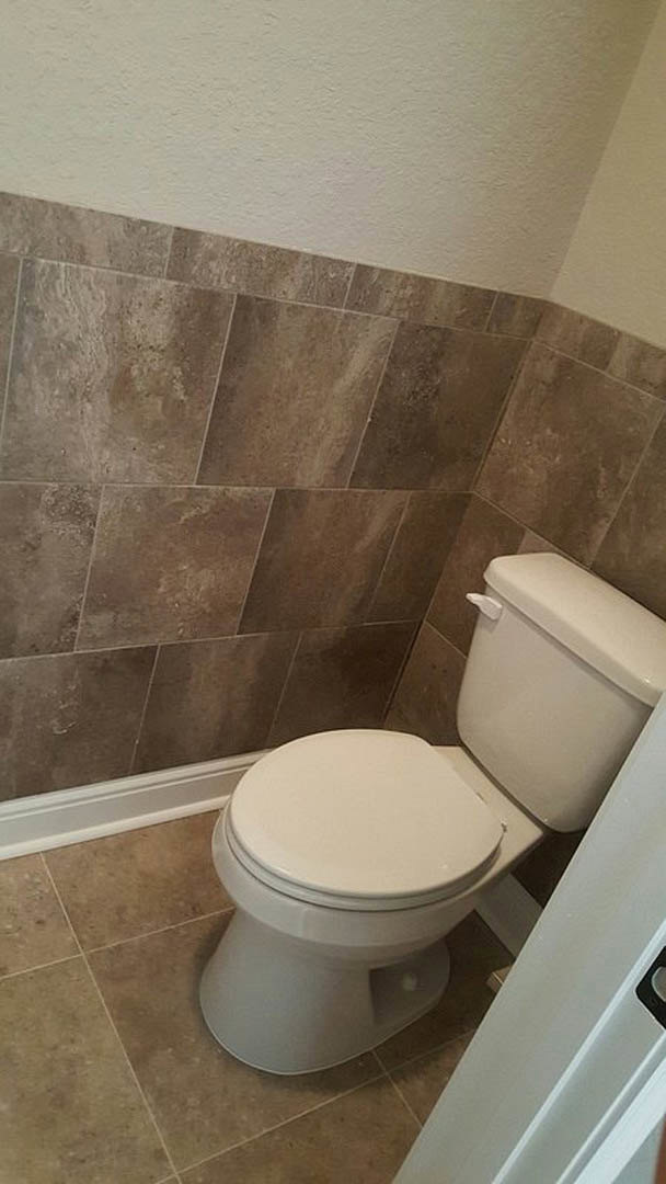White toilet with closed lid beside tiled wall and floor in modern bathroom