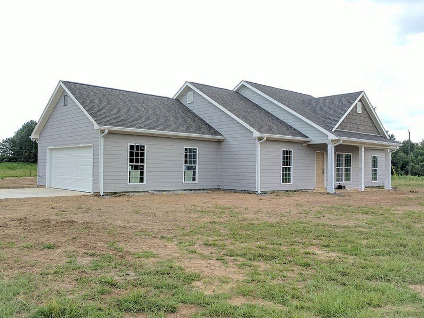 White-sided house with large grassy yard, white-framed window, white garage door, and shingled roof; Robert Frost Farm visible in the background.