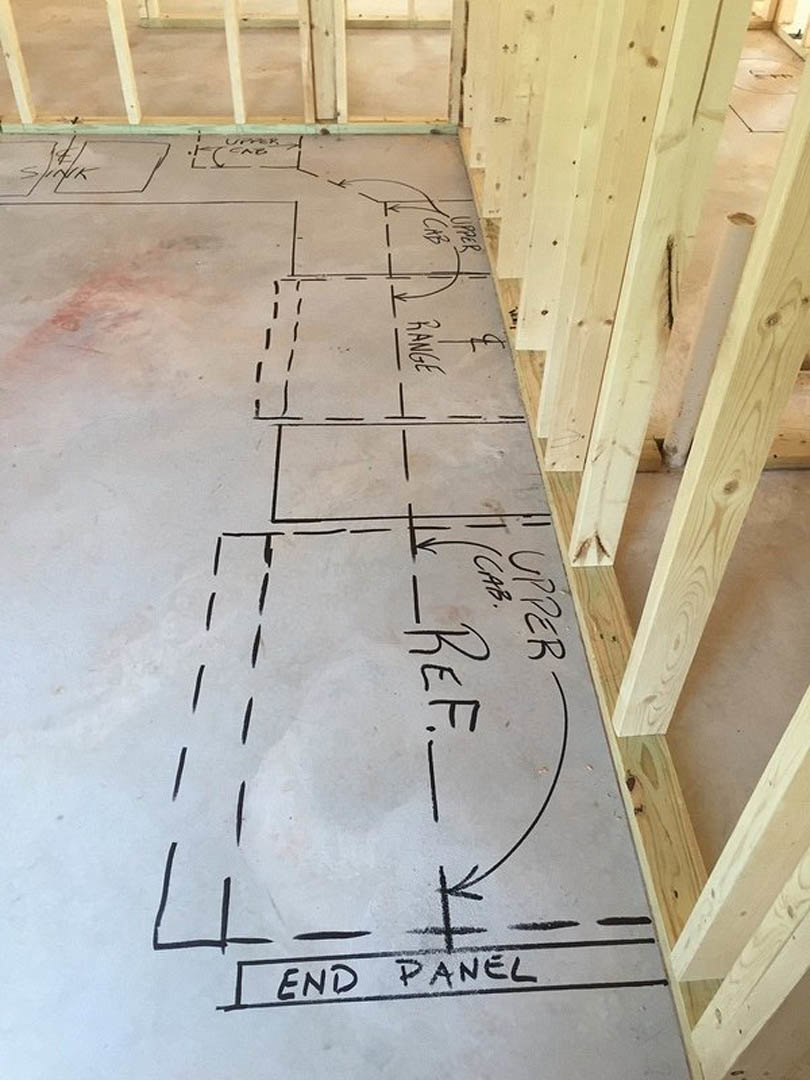 Concrete floor with black lines and handwritten words, wooden ceiling beam above, close-up of wood planks nearby